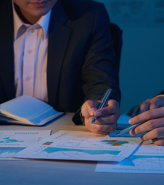 Business professionals reviewing charts and reports on a desk under blue lighting