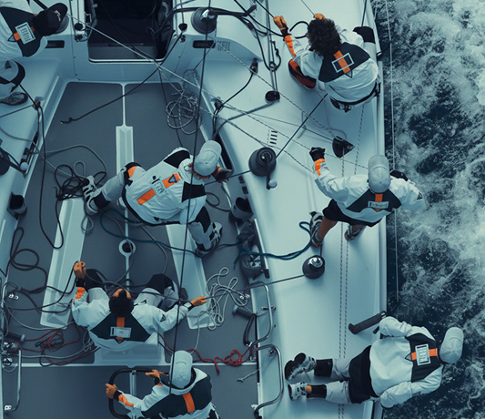 Aerial view of a sailing crew working together on a racing yacht deck