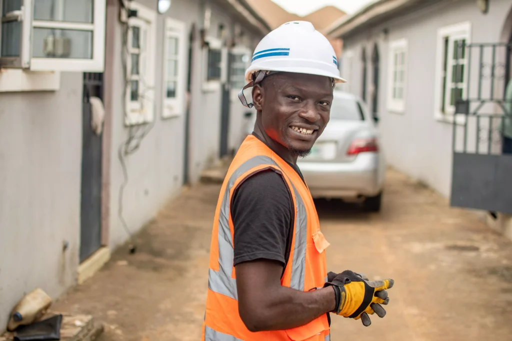 a-man-wearing-a-hard-hat-and-orange-vest-smiles