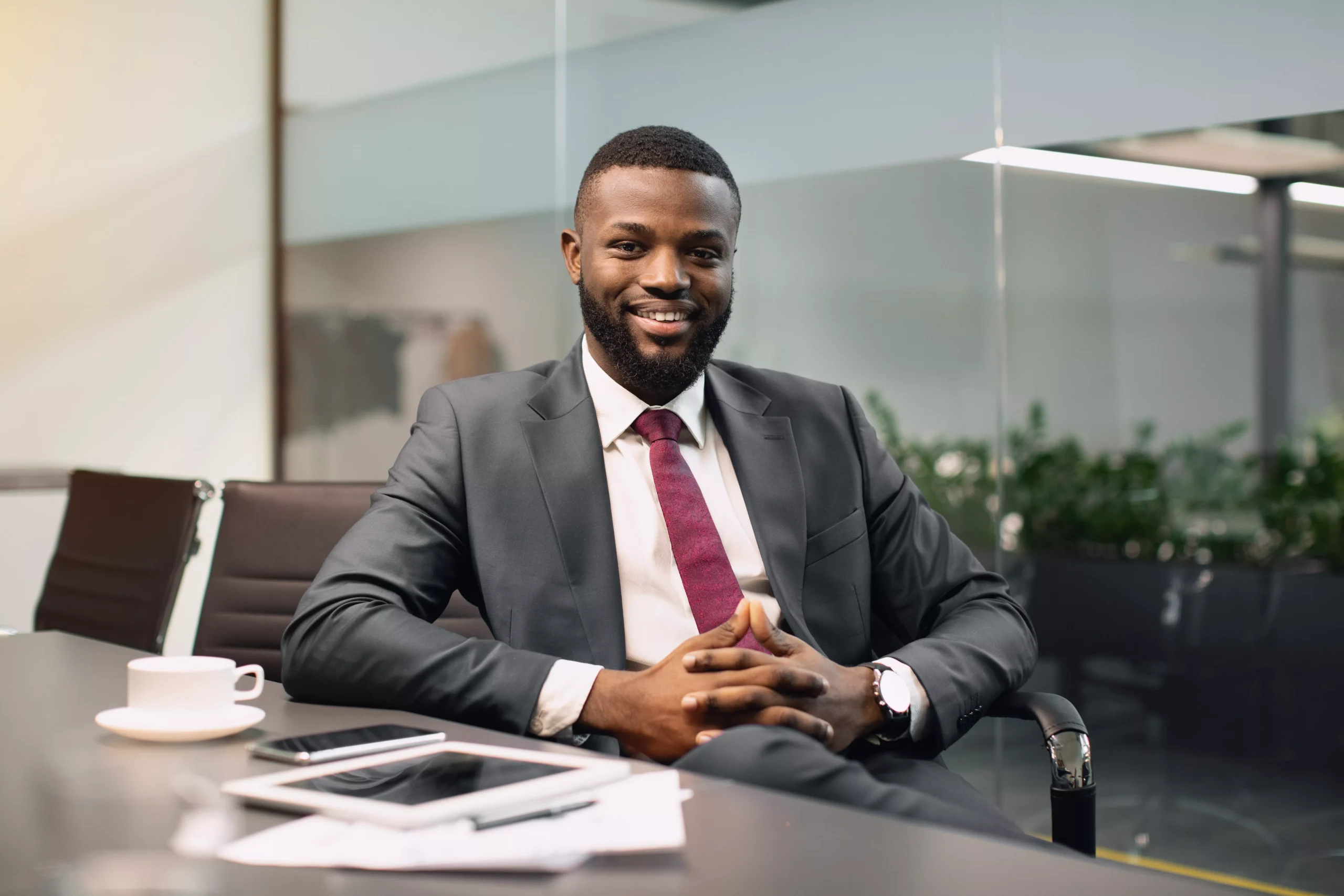 cheerful-black-guy-ceo-sitting-at-conference-hall