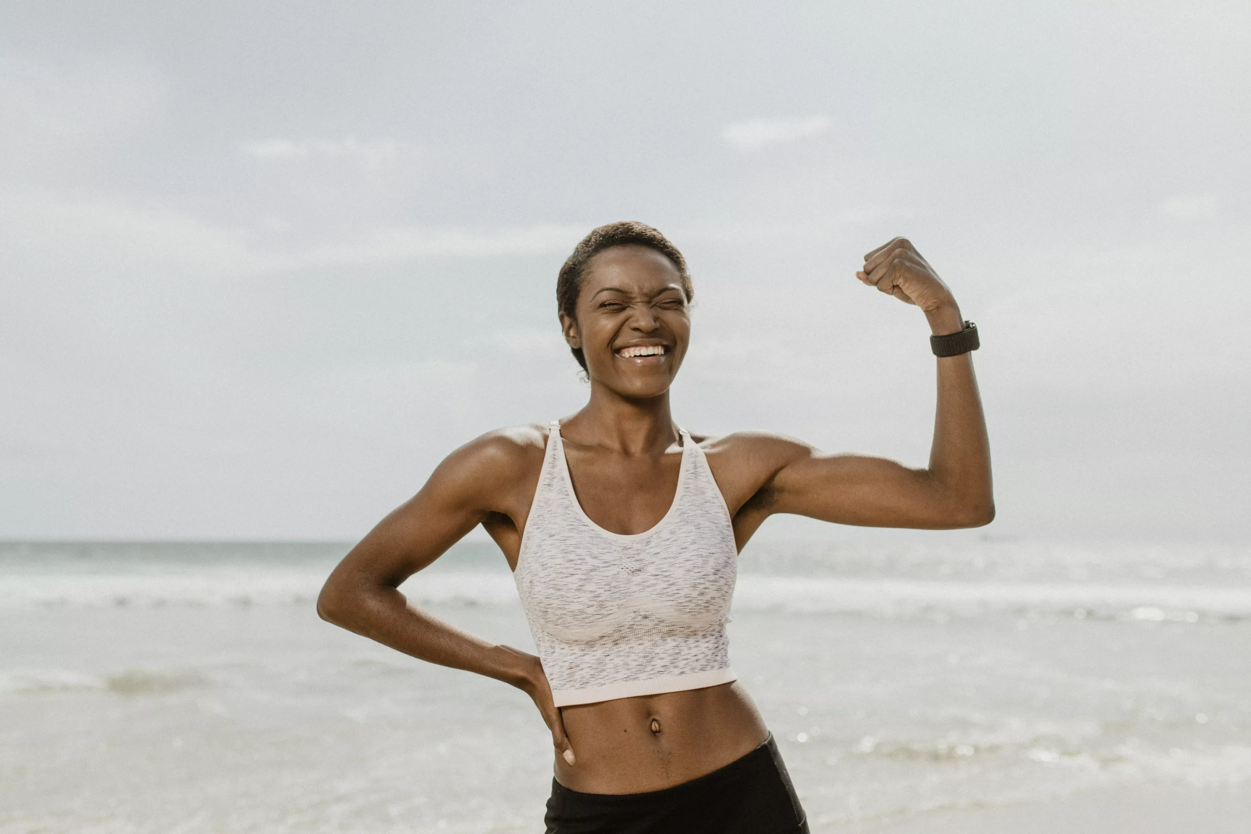 cheerful-black-woman-flexing-her-muscles-by-the-se