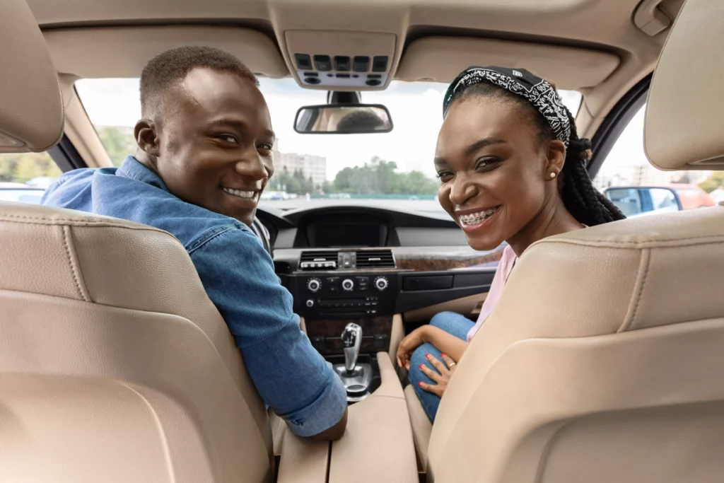 happy-afro-american-couple-posing-in-auto-looking