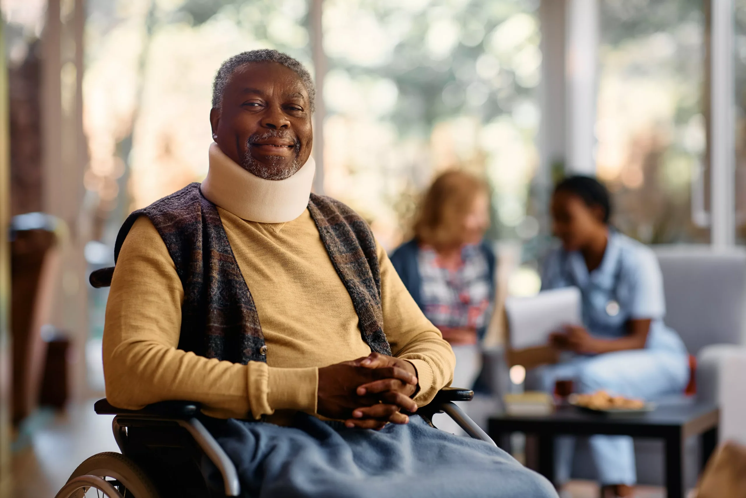 happy-black-senior-man-with-neck-collar-sitting-in