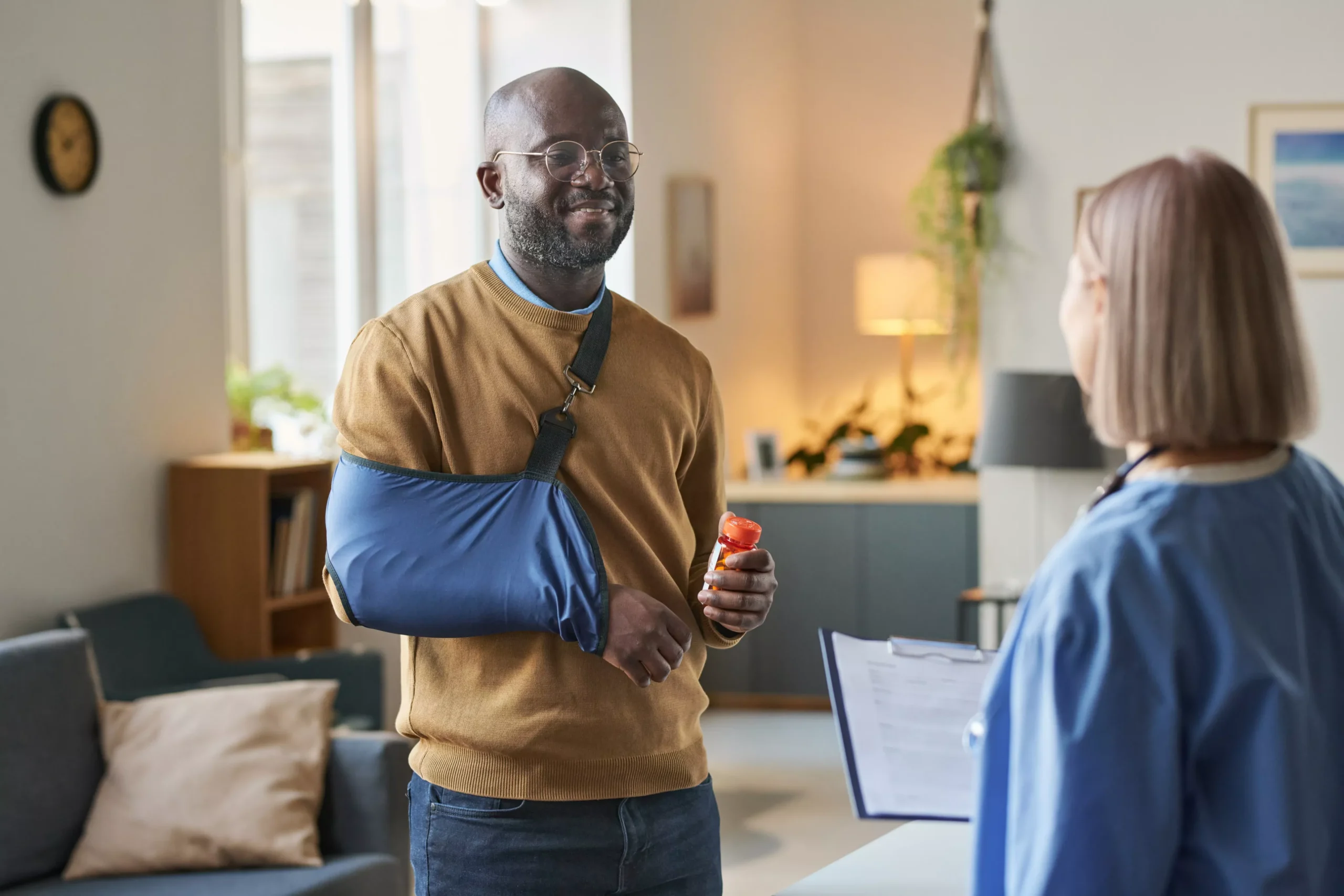 smiling-black-man-with-broken-arm-talking-to-nurse