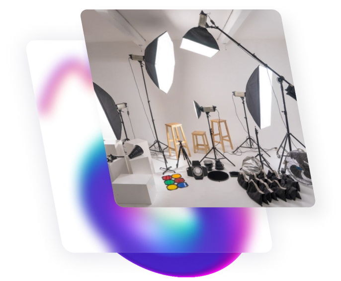 A creative studio with white background filled with four big photo lighting, three wooden chair and other properties.